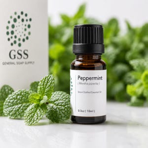 May include: A small amber glass bottle of peppermint essential oil with a black cap and a white label reading Peppermint, Mentha piperita, Steam Distilled Essential Oil, and 0.3oz (10ml). A white box with a green dotted logo is visible.