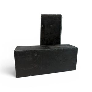 May include: Two rectangular, solid black blocks are displayed against a white background. One block is upright, while the other rests horizontally. The blocks have a matte finish and appear to be made of a dense material.