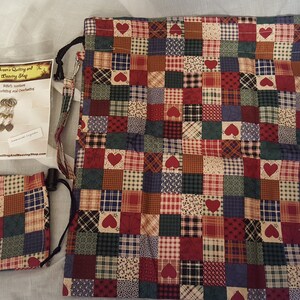 May include: A red, green, blue, and white patchwork fabric drawstring bag with a heart pattern. The bag has a small tag that says "Grandma's Quilting and Sewing Shop".