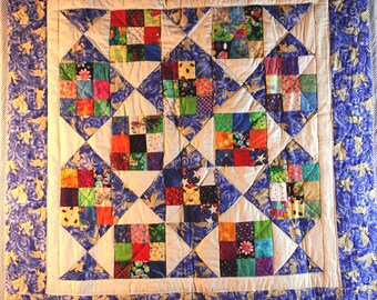 May include: A patchwork quilt with a white background and a blue border. The quilt is made up of many small squares of different colors and patterns. The squares are arranged in a geometric pattern.