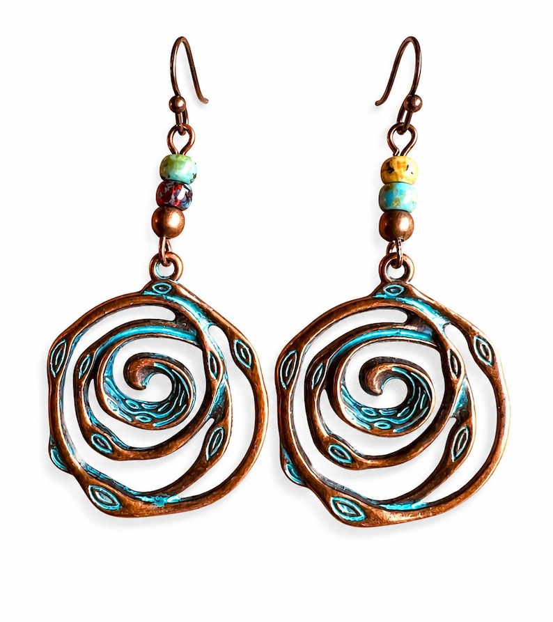 May include: A pair of copper-toned earrings with a spiral design and turquoise detailing. Each earring has a series of colourful beads and a hook fastening. The earrings have an openwork design with a vintage aesthetic.