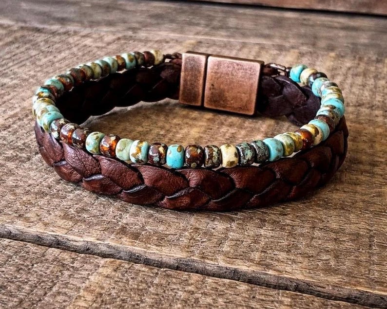 Braided brown leather bracelet with turquoise and brown beaded accents. The bracelet features a copper-colored magnetic clasp. A stylish accessory for everyday wear.