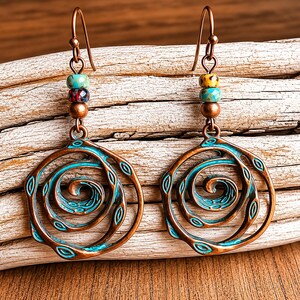 May include: A pair of copper-toned earrings with a spiral design. The earrings feature a turquoise and copper colour scheme, with a series of colourful beads at the top. The spiral design is accented with turquoise details, creating a unique and artistic look.