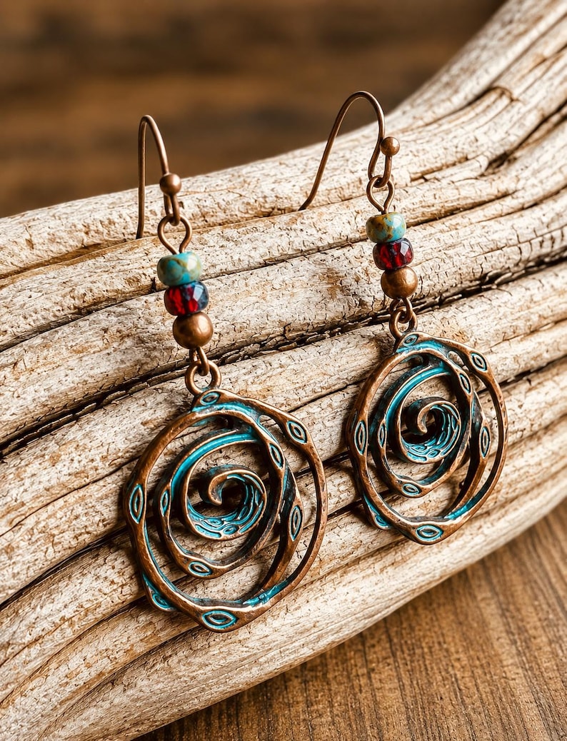 May include: Copper-coloured earrings with a spiral design. The earrings have a turquoise and red beaded accent above the spiral. The spiral design is outlined in turquoise and has small oval cutouts. The earrings hang from a copper-coloured hook.