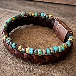 Braided brown leather bracelet with turquoise and multicolored beads. The bracelet features a copper-colored magnetic clasp. The beads are a mix of blue, green, yellow, and red.