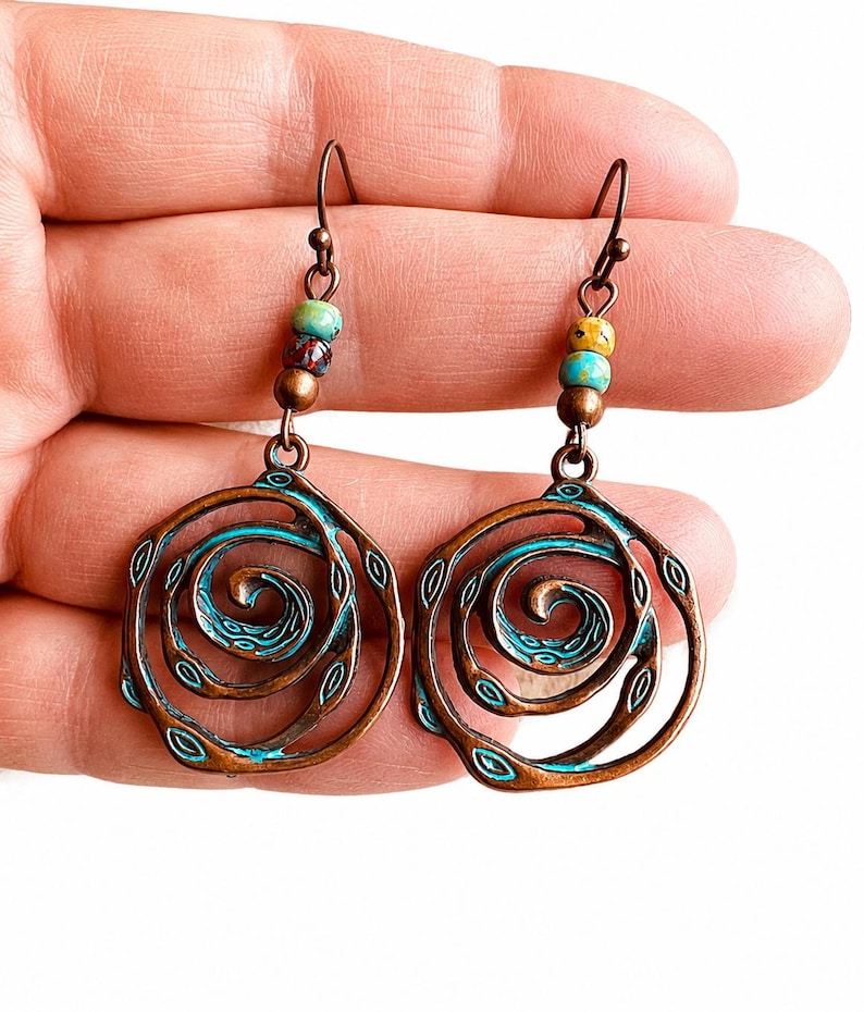 May include: A pair of copper-coloured spiral earrings with turquoise accents. Each earring features a spiral design with small, colourful beads at the top. The earrings are designed with a hook closure.