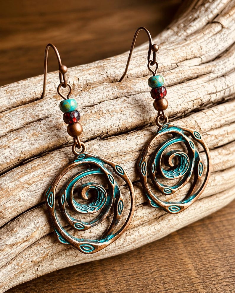 May include: A pair of copper-toned earrings featuring a spiral design with turquoise and red beads. The earrings have a hook fastening and a distressed finish, ideal for a bohemian or nature-inspired style.