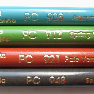 Op de afbeelding: Vier kleurpotloden met gouden letters. De potloden zijn gelabeld met "Azul Aguamarina PC 905 Aquamarine", "Verde Primavera PC 913 Spring Green", "Bermell&oacute;n P&aacute;lido PC 921 Pale Vermilion" en "Sepia PC 948 Sepia".