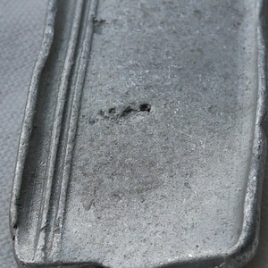 May include: A close-up of a silver metal bar with a textured surface. The bar has a slightly curved shape and a smooth, polished finish.