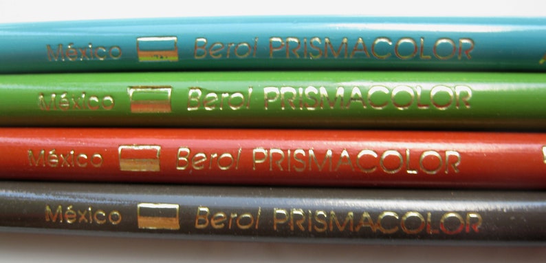 Op de afbeelding: Vier kleurpotloden met gouden opschrift "M&eacute;xico" en "Berol PRISMACOLOR". De potloden zijn turquoise, groen, rood en bruin.