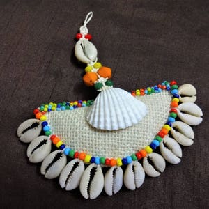 May include: A handmade wall hanging with a white seashell, colorful beads, and a burlap background. The seashells are arranged in a semi-circle shape.