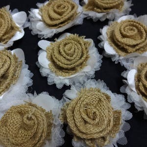 May include: A collection of nine brown burlap fabric flowers with white lace trim. The flowers are arranged in a circular pattern on a black background.