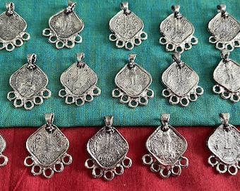May include: A collection of silver-toned pendants featuring a square design with a coin-like image in the center. Each pendant has five loops at the bottom for attaching to a chain or cord.