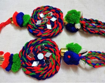 May include: Two handmade red, blue, and green tassel ornaments with mirrored accents. Each tassel has a round, woven center with a gold metal ring.