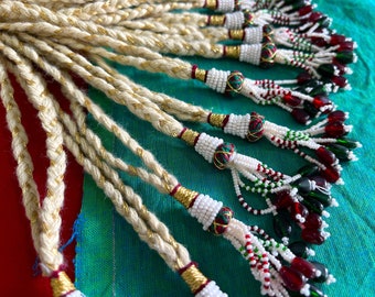 May include: A collection of braided cords with gold thread accents and decorative tassels. The tassels are made with white, red, and green beads and have small, red, and green glass beads hanging from them.
