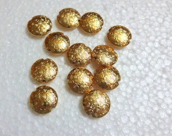 May include: A collection of 12 gold-colored metal buttons with a swirl pattern. The buttons are round and have a flat back.