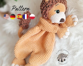 May include: A crocheted lion lovey toy made of soft tan and brown yarn. The lion has a brown textured mane, a white muzzle with a dark brown nose, and green eyes. The body is flat with four paws featuring white accents. Text reads Pattern.