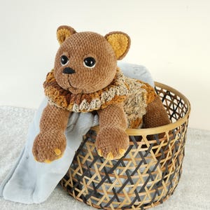 May include: A brown plush toy cat with a brown and orange knitted scarf, sitting in a woven basket.