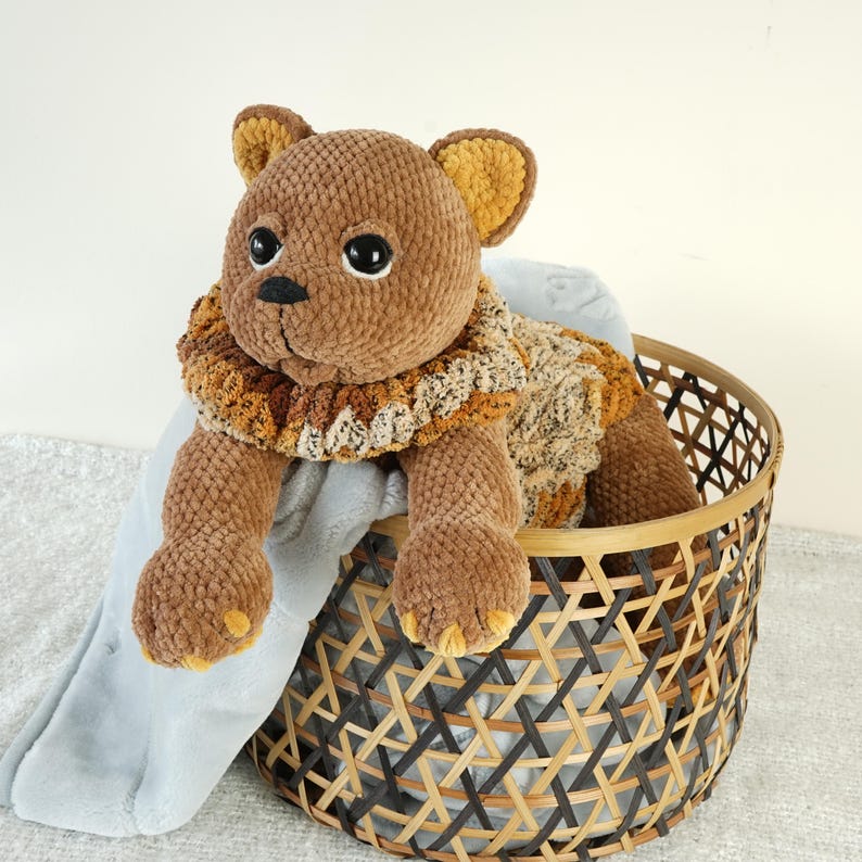 May include: A brown plush toy cat with a brown and orange knitted scarf, sitting in a woven basket.