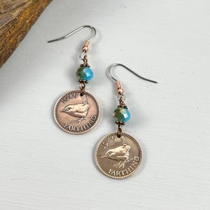 May include: Earrings made from 1945 farthing coins, featuring a bird design. Each earring has a teal bead and a copper hook. The coins are copper-colored and the word "FARTHING" is around the edge.