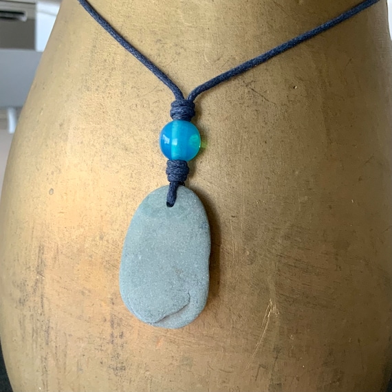 Raw stone pendant necklace handmade using a natural found beach stone with a bright blue bead on an adjustable dark blue waxed cotton cord