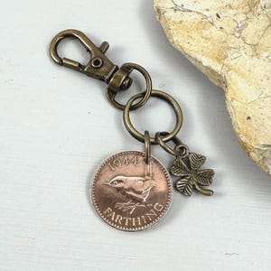 May include: Vintage bronze keyring with a 1944 Farthing coin depicting a bird, and a small four-leaf clover charm. The keyring includes a lobster clasp for attachment.