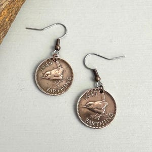 May include: A pair of earrings made from vintage 1945 farthing coins. Each coin shows a bird and the word "FARTHING". The earrings have silver-colored hooks and bronze-colored connectors. A unique, vintage accessory.