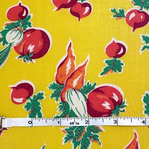May include: Yellow fabric with a repeating pattern of red tomatoes, orange carrots, and green leaves. The design includes white onions and a measuring tape showing 4 inches.