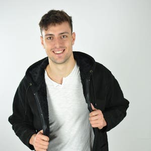 Peut inclure: Une veste noire à capuche avec une fermeture éclair et une doublure en polaire. La veste a une capuche avec cordon de serrage et deux poches.