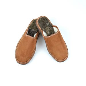 May include: A pair of brown suede slippers with a white trim and a fuzzy brown lining.