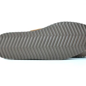 May include: Close-up of the bottom of a brown leather sandal with a textured rubber sole.