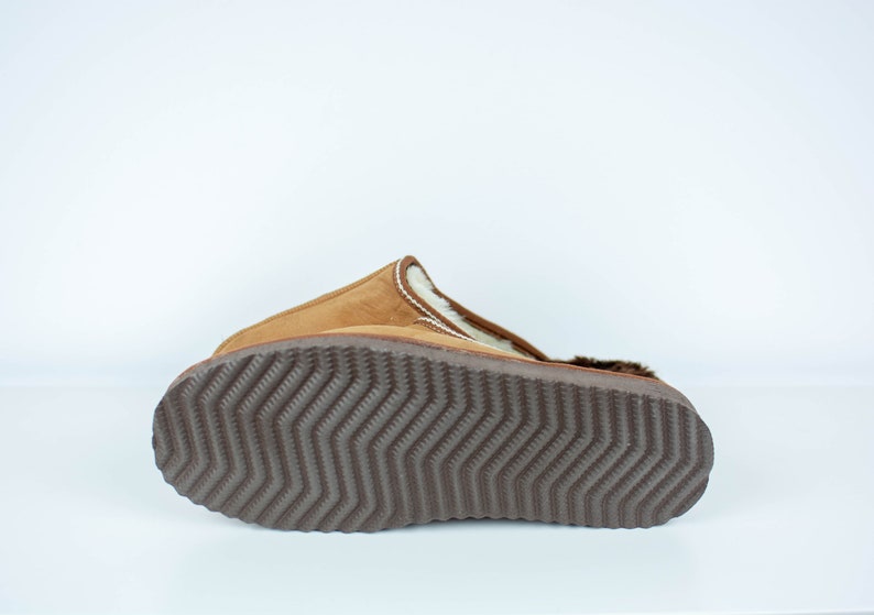 May include: Brown suede slipper with a white faux fur lining and a brown rubber outsole with a textured tread pattern.