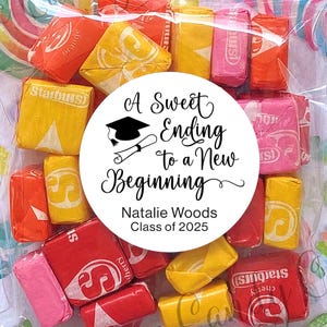 May include: A clear plastic bag filled with colorful Starburst candies. A white circle sticker with black text reads "A Sweet Ending to a New Beginning" with a graduation cap icon. The text below the circle reads "Natalie Woods Class of 2025".