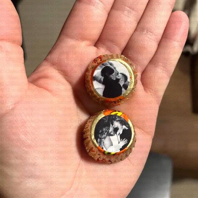 May include: Two round, orange and gold candy wrappers with black and white photos of couples kissing. The wrappers have the text "Classic Candy Covers" printed on them.