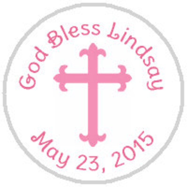 May include: A white circle with a pink cross in the center. The text "God Bless Lindsay May 23, 2015" is written around the cross.