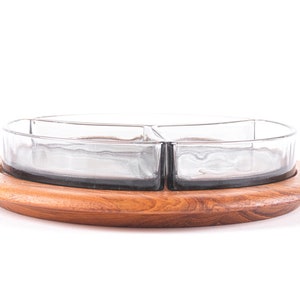Puede incluir: Una bandeja redonda de madera para servir con tres cuencos de vidrio. La bandeja es de madera marrón claro y los cuencos son de vidrio transparente.