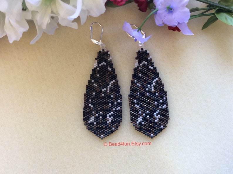 Peut inclure: Une paire de boucles d'oreilles pendantes en forme de larme. Les boucles d'oreilles sont faites de perles noires, blanches et brunes et ont un crochet argent&eacute;.