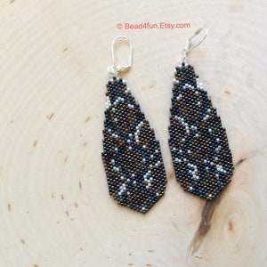 Peut inclure: Une paire de boucles d'oreilles pendantes avec un motif g&eacute;om&eacute;trique noir, blanc et marron. Les boucles d'oreilles sont faites de petites perles et ont des crochets argent&eacute;s.