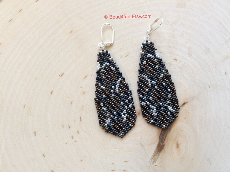 Peut inclure: Une paire de boucles d'oreilles pendantes avec un motif g&eacute;om&eacute;trique noir, blanc et marron. Les boucles d'oreilles sont faites de petites perles et ont des crochets argent&eacute;s.