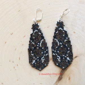 Peut inclure: Une paire de longues boucles d'oreilles en forme de goutte d'eau avec un motif g&eacute;om&eacute;trique noir, brun et blanc. Les boucles d'oreilles sont faites de perles de rocaille et ont des crochets argent&eacute;s.