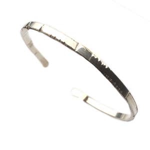 May include: A silver bracelet with a textured surface.