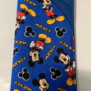 May include: Blue fabric item featuring a repeating pattern of Mickey Mouse illustrations in red, yellow, black, and white. The word "Mickey" is printed in yellow. The item has a solid blue flap.