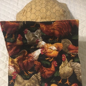May include: A quilted fabric item featuring a black background with a repeating pattern of colorful chickens in various poses. The chickens are in shades of red, brown, white, and tan. The item is paired with a tan, hexagonal patterned item.