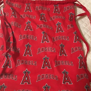 Puede incluir: Bolsa roja con cord&oacute;n con un patr&oacute;n repetido de la palabra "ANGELS" y el logotipo "A" del equipo en blanco y negro. La bolsa tiene cordones rojos y es de tela.