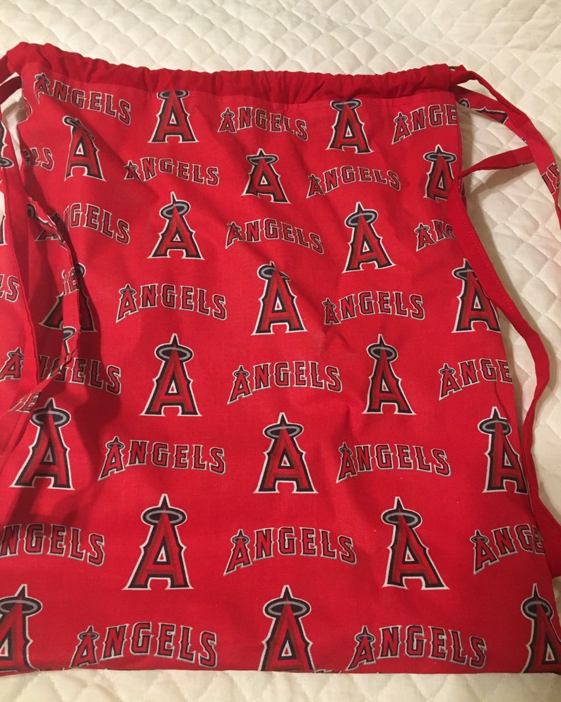 Puede incluir: Bolsa roja con cord&oacute;n con un patr&oacute;n repetido de la palabra "ANGELS" y el logotipo "A" del equipo en blanco y negro. La bolsa tiene cordones rojos y es de tela.