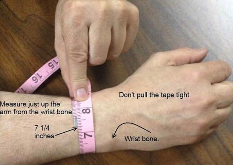 May include: A pink measuring tape is wrapped around a person's wrist to show how to measure for a bracelet. The tape measure reads 7 1/4 inches. The text says "Measure just up the arm from the wrist bone. Don't pull the tape tight. Wrist bone."