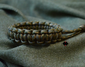 May include: A green and brown paracord bracelet with a knotted closure.