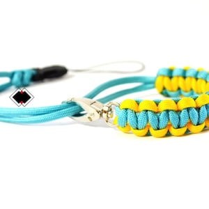 May include: A blue and yellow paracord lanyard with a silver clasp. The lanyard is made of braided cord and has a simple design.