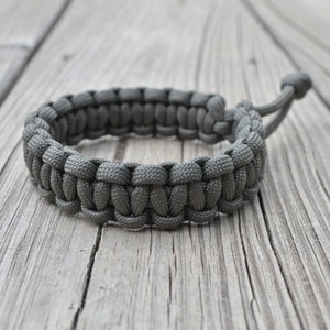 May include: A gray paracord bracelet with a simple knot design.