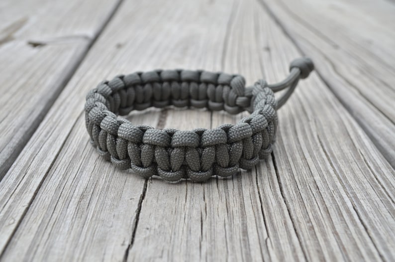 May include: A gray paracord bracelet with a simple knot design.